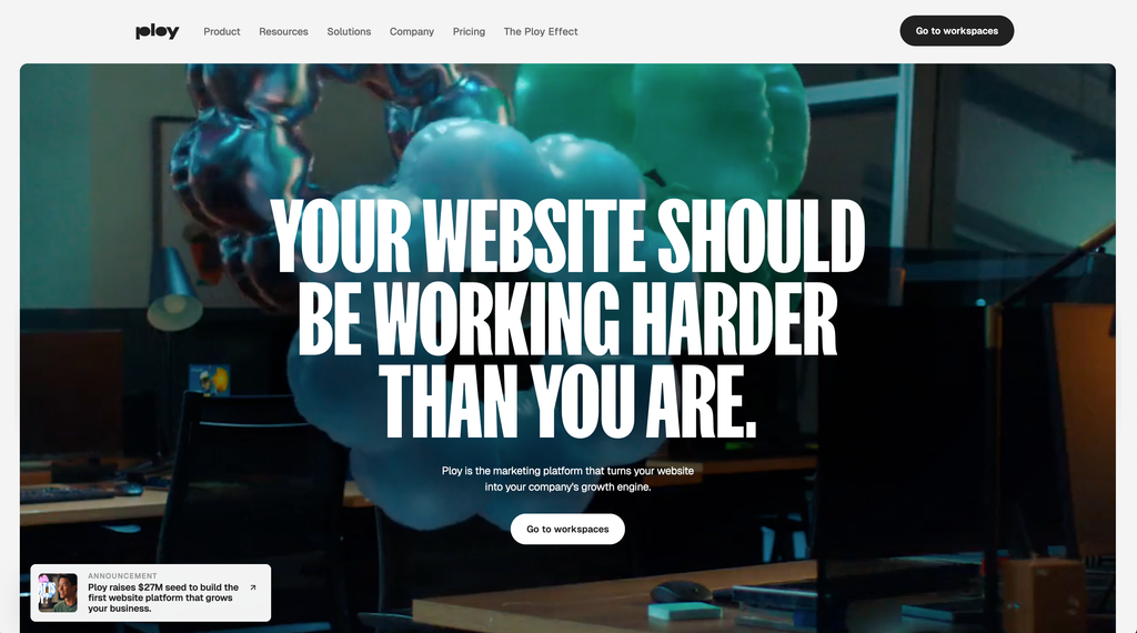 Startseite einer Website mit dem Text "YOUR WEBSITE SHOULD BE WORKING HARDER THAN YOU ARE" auf einem Hintergrund mit Büroeinrichtung und Luftballons.